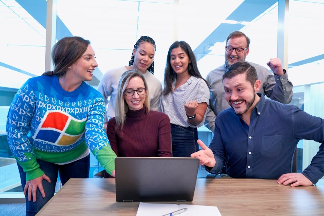 Team gathered around a table reacting to information on a laptop screen
